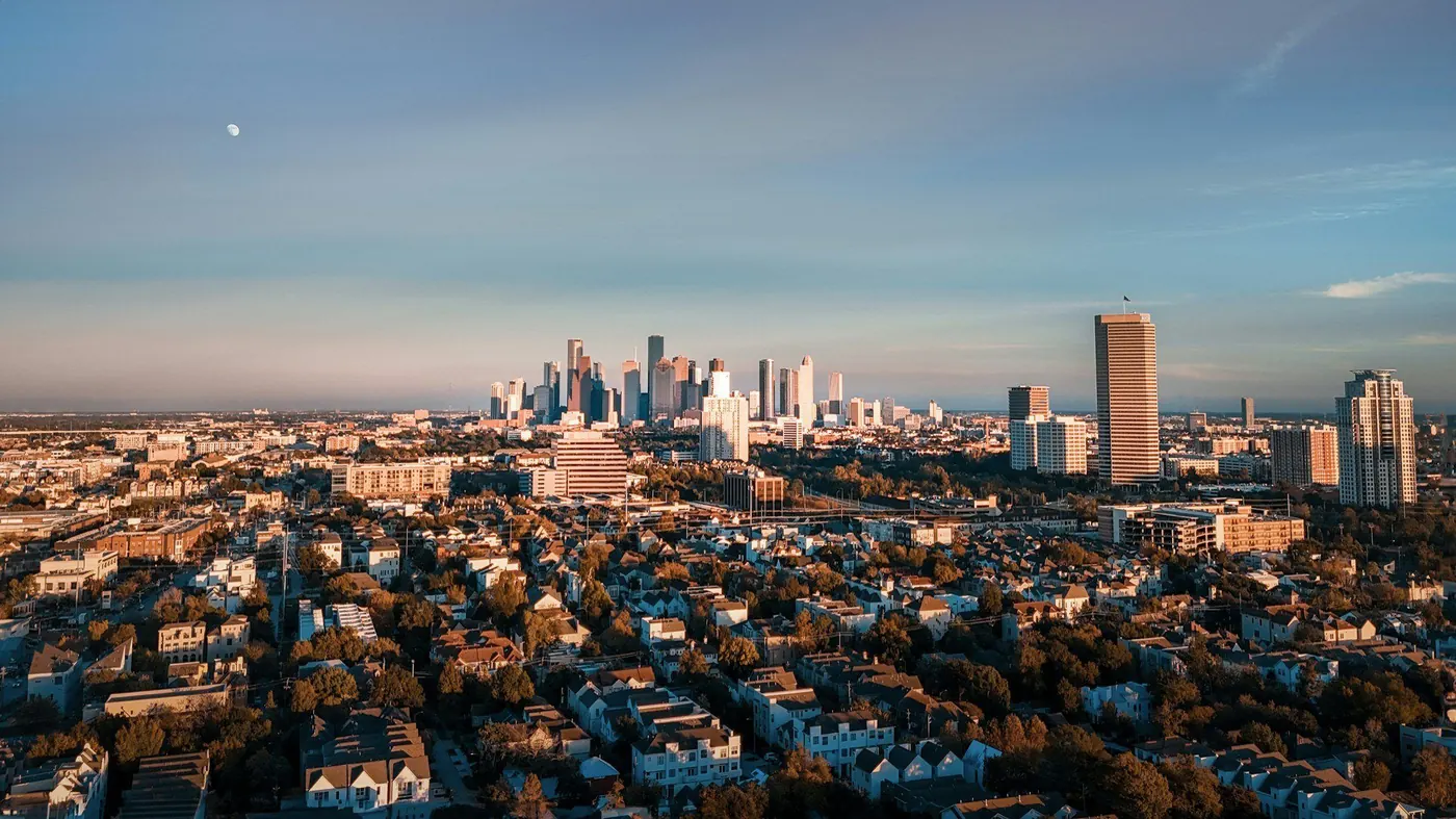 Aerial view of Houston at dusk, neighborhoods in the foreground and the skyline on the horizon